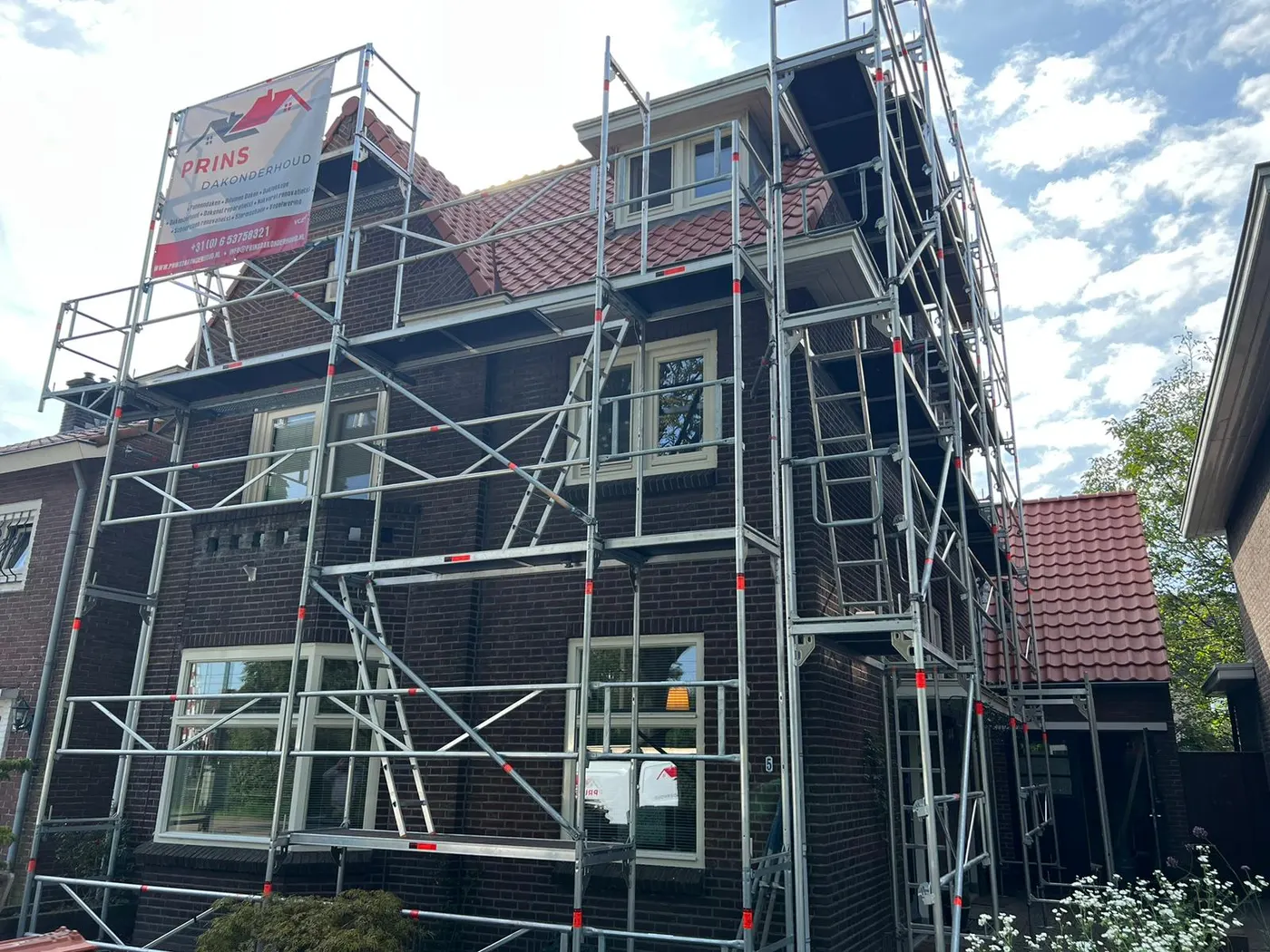 Steiger met het spandoek van Prins Dakonderhoud bij een pannendakrenovatie